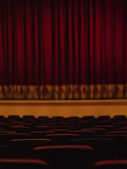 Widownia teatralna z czerwoną kurtyną w tle